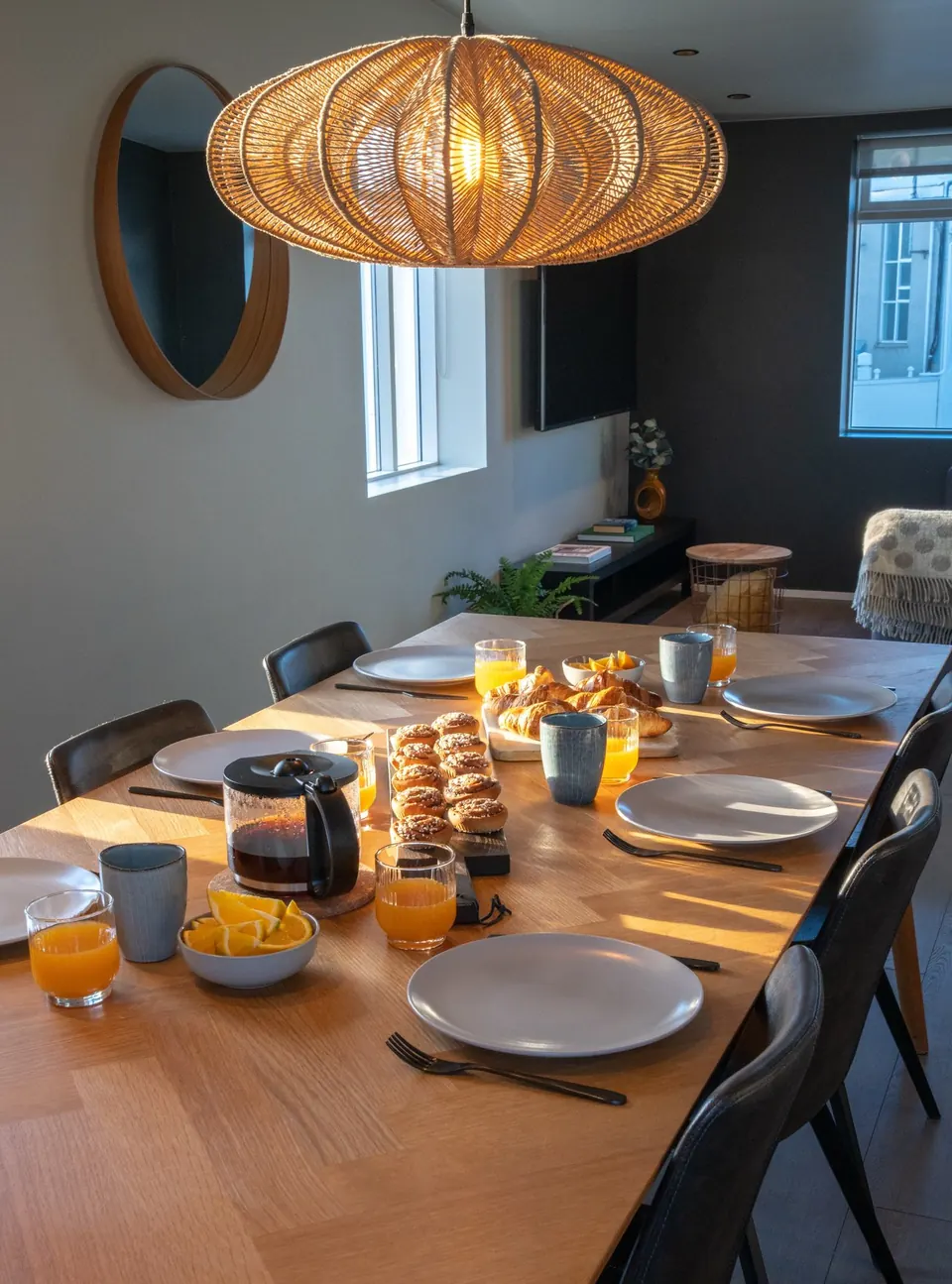 Breakfast laid on a long oak table under a rattan lamp