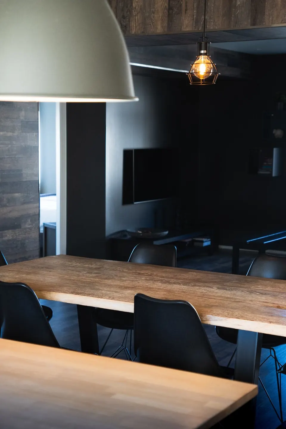 Caged pendant bulb glowing over an oak dining table