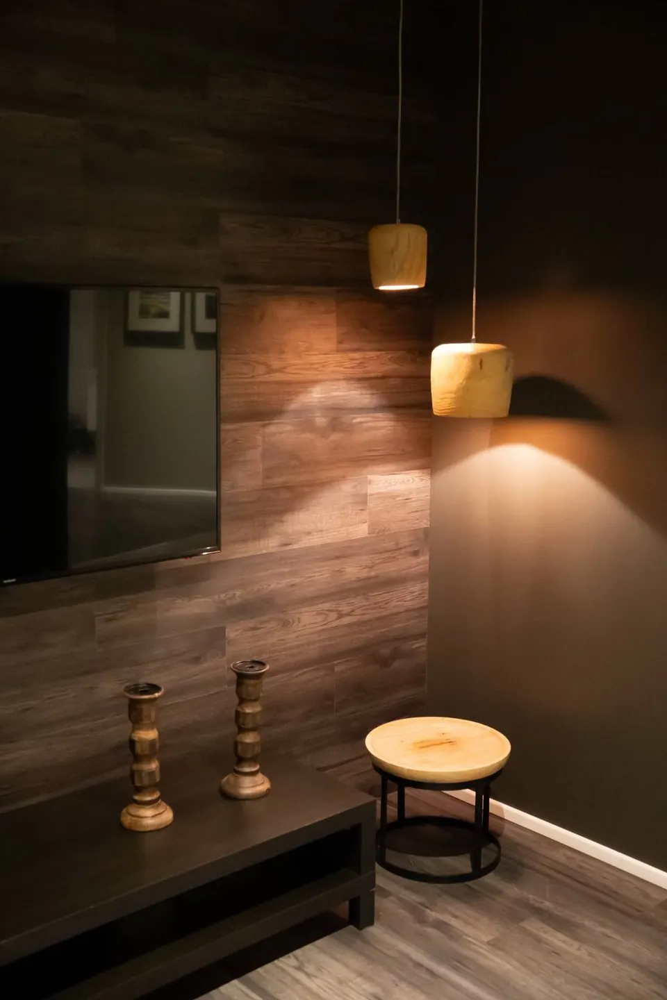 Wooden pendant lamps glowing against a dark wood-panelled wall